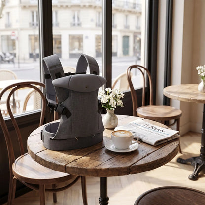 Porte bebe physiologique déposé sur une table dans un bistro