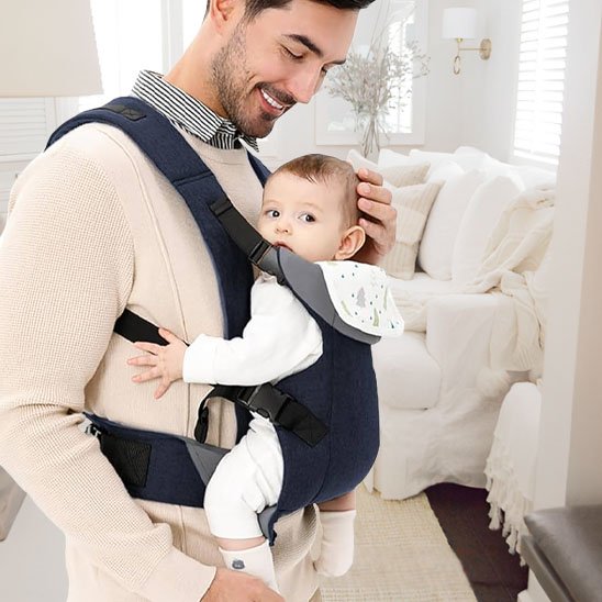 Papa se promène dans le salon avec fiston dans le Porte-bébé physiologique  ventre contre ventre