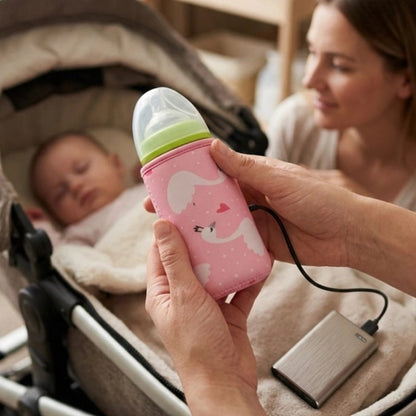 Papa utilise le Chauffe biberon nomade cygne pendant que maman regarde bébé endormi dans la poussette
