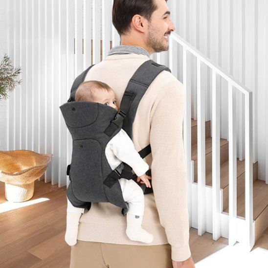 Papa va a l'étage avec bébé qui est dans le Porte-bébé physiologique face à son dos 